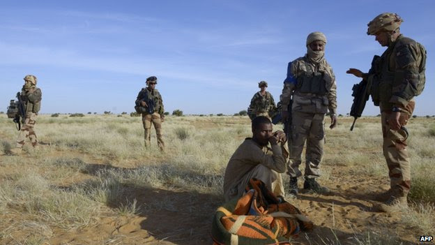 French soldiers stand next to a nomad in desert between Timbuktu and Gao on 30 October 2013