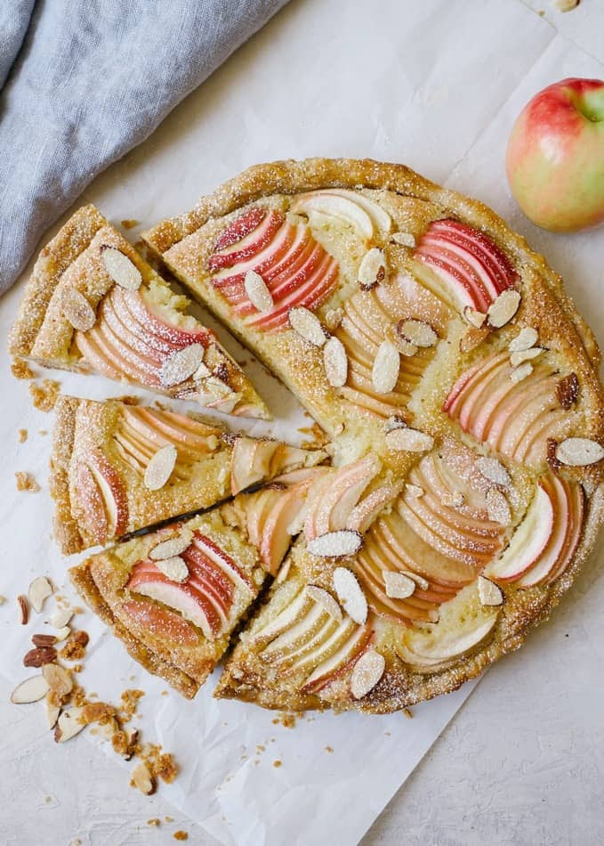 Apple Frangipane Tart by Wood and Spoon blog. This is an elegant holiday tart with a flaky pie crust, and almond filling and beautiful apples on top. Served with a glass of wine this is the French treat your holiday guests will go crazy for! This fancy dessert is made in a tart pan and easily serves a crowd. Find out more about the recipe on thewoodandspoon.com