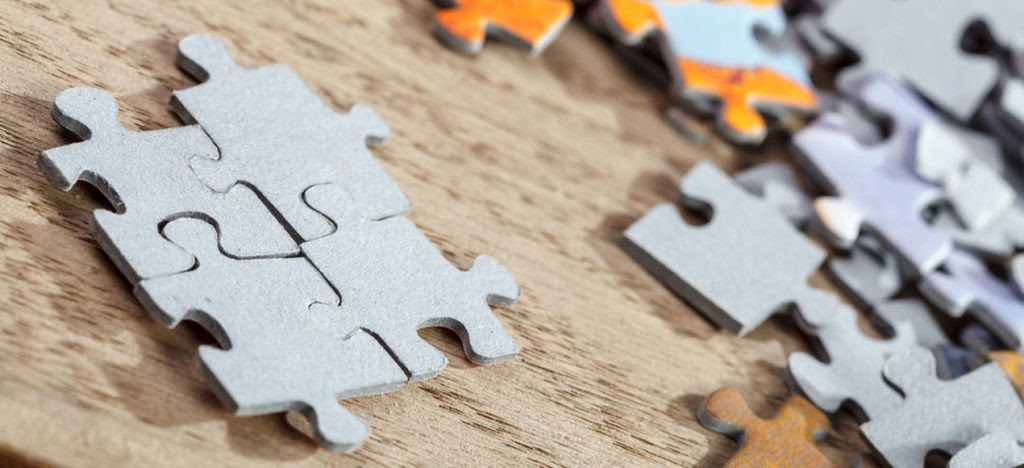 Closeup of four connected jigsaw puzzle pieces on a table.