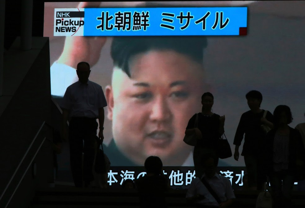 Pessoas passam por uma TV em Tóquio, no Japão, que exibe a imagem do líder norte-coreano Kim Jong Un enquanto relata o teste de mísseis da Coreia do Norte que caiu no mar do país (Foto: Eugene Hoshiko/AP)