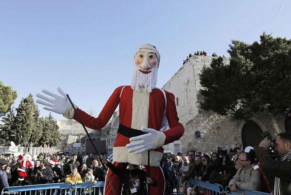 Celebrations: A performer entertains children with a giant Santa Claus puppet at a Christmas parade in Manger Square