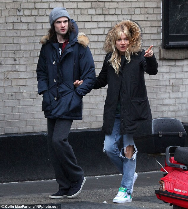 In the hood: Sienna covers up with a big fur hood as she walks around a rainy New York with boyfriend Tom Sturridge