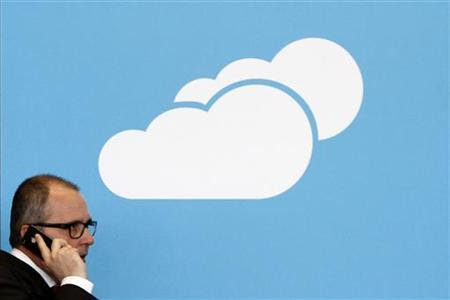 A visitor uses his mobile phone as he walks past the Microsoft booth with a logo for cloud computing software application at the CeBit computer fair in Hanover, March, 6, 2012. REUTERS/Fabrizio Bensch/Files