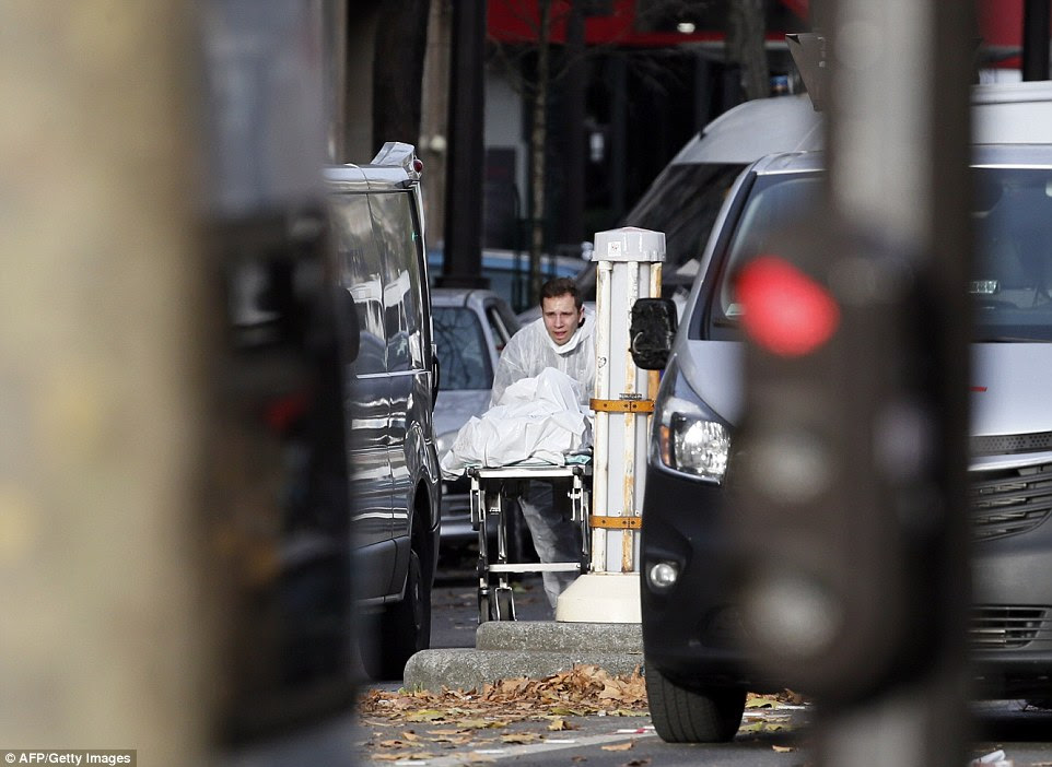 A medic takes a victim's body away from the scene of the Bataclan concert hall where up to 100 fans were shot dead at a heavy metal gig