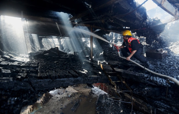 A Palestinian firefighter hoses a boat hit in an missile strike at the port in Gaza City.