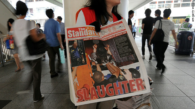 A news agent hands out free newspapers in Hong Kong on Tuesday with headlines and photos about the bus hijacking crisis in Manila the previous day.