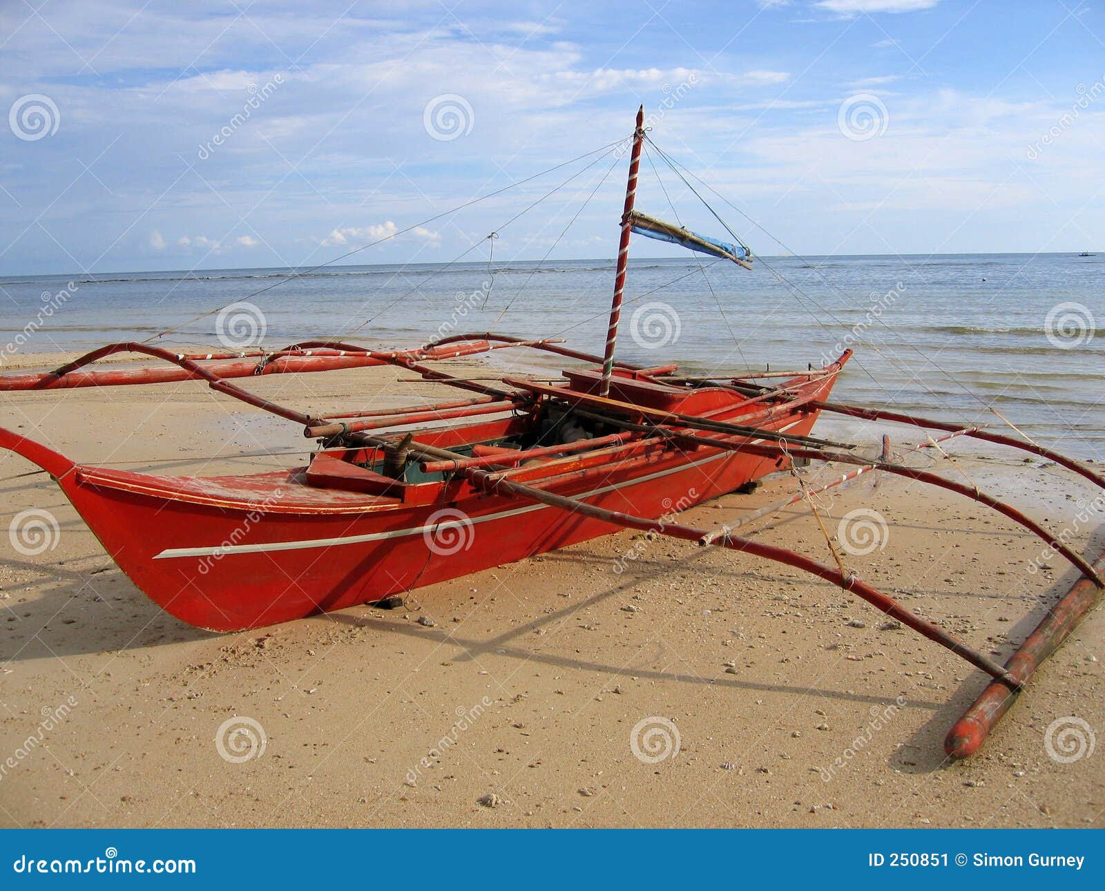 Small red Banca traditional outrigger fishing boat on the beach negros 