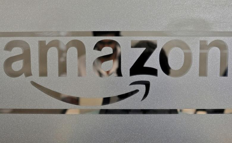 FILE PHOTO: Employees of Amazon India are seen behind a glass bearing the company's logo inside its office in Bengaluru, India, August 14, 2015. REUTERS/Abhishek N. Chinnappa/File Photo