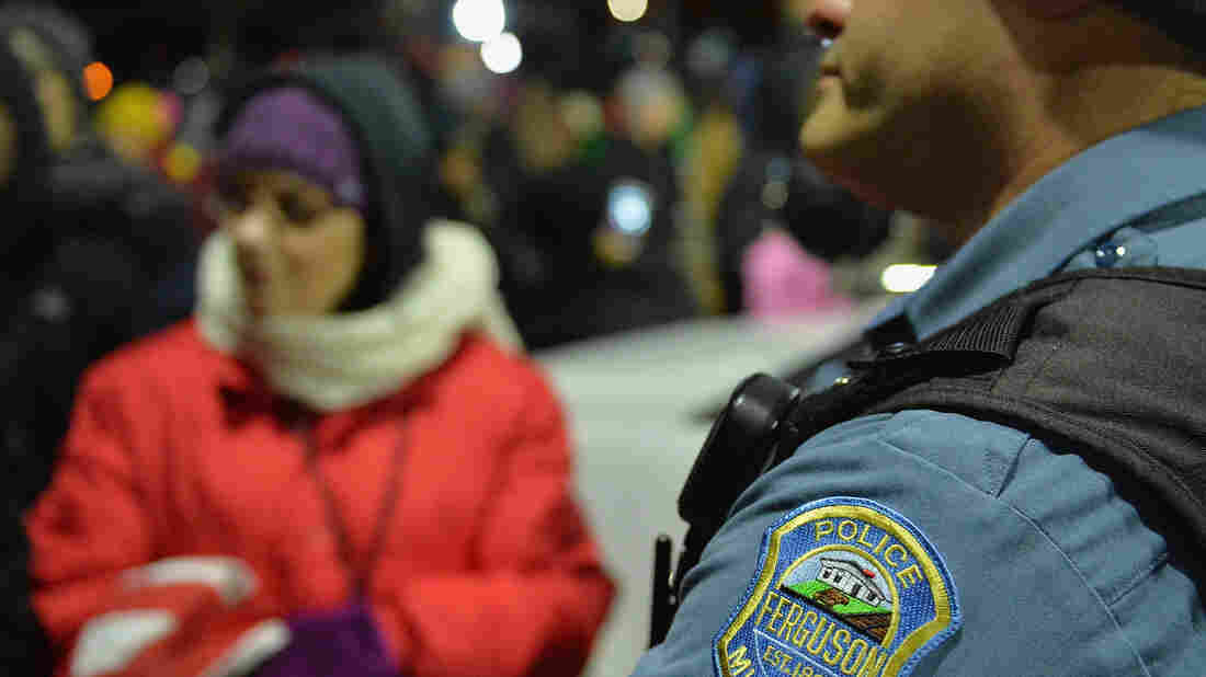A Ferguson police officer listens to a protester outside the Ferguson Police Department on Wednesday.