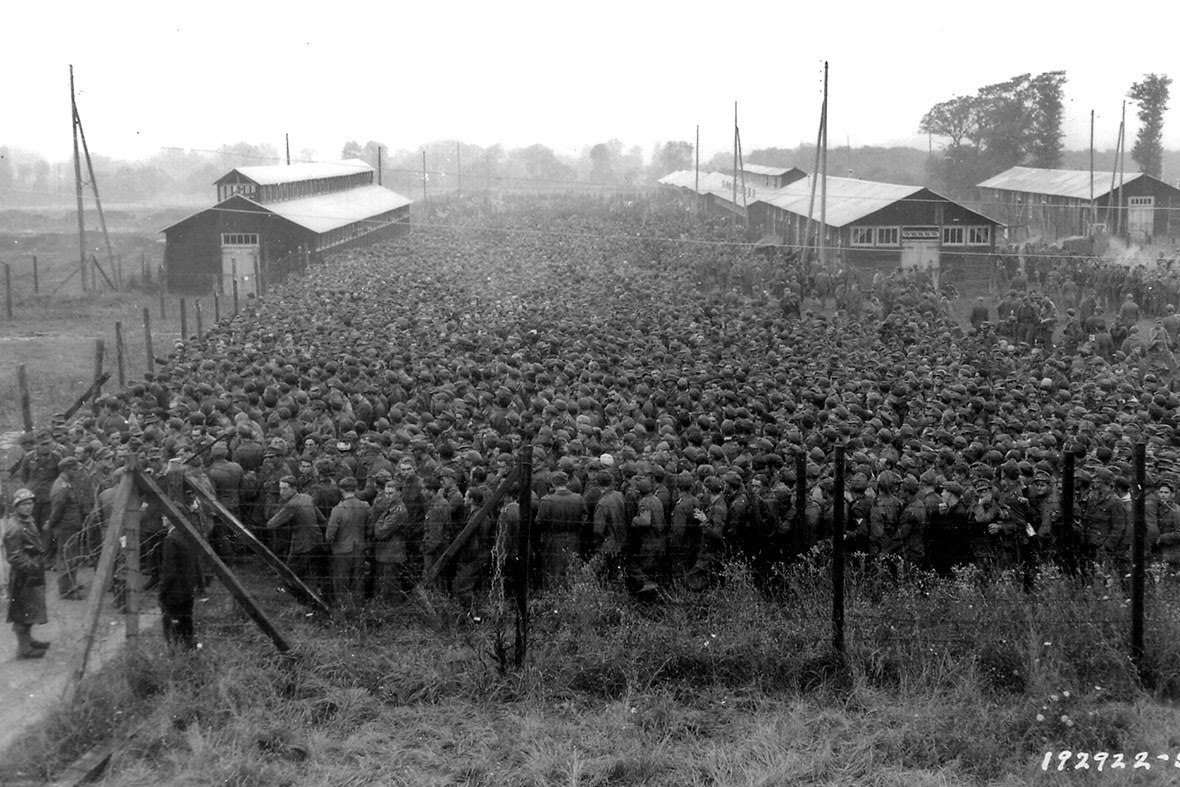 August 21, 1944: German prisoners of war captured after the D-Day landings in Normandy are guarded by US troops at a camp in Nonant-le-Pin, France