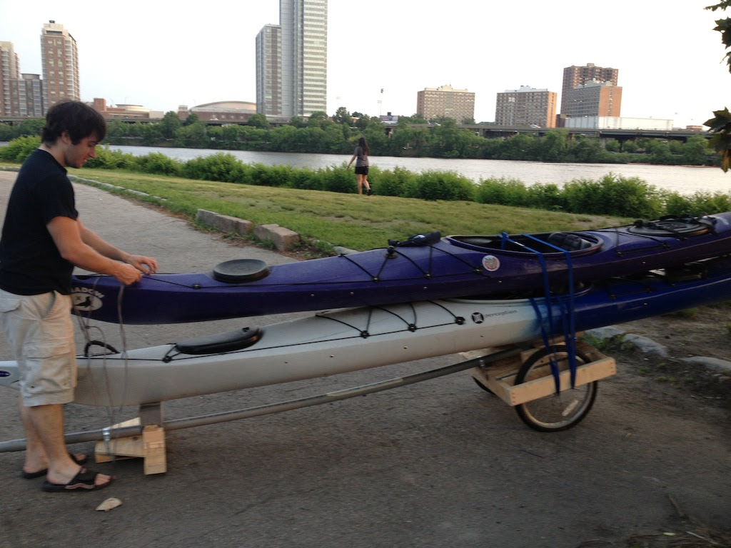 Two sea kayaks being towed by a bicycle at the Charles River
