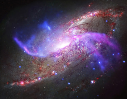 A new composite of NGC 4258 features X-rays from Chandra (blue), radio waves from the VLA (purple), optical data from Hubble (yellow and blue), and infrared with Spitzer (red). Image Credit: Chandra