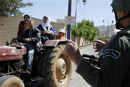 A family riding on a tractor pass a Syrian soldier at a checkpoint, during a field visit made by United Nations (U.N.) observers to the Madaya area, near Damascus May 6, 2012. REUTERS/Khaled al- Hariri