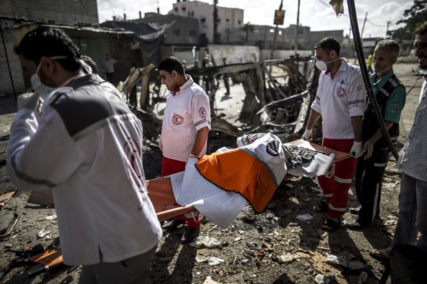  Palestinos carregam o corpo carbonizado de um motorista de ambulância, morto na noite de sexta-feira em Beit Hanun, na Faixa de Gaza (Foto: AFP Photo/Marco Longari)