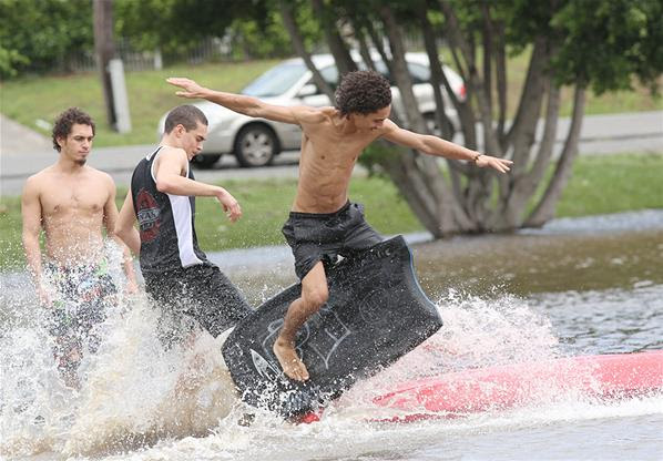 Derasnya banjir di membuat warga bermain ski di Warga bermain papan selancar di derasnya banjir Downey Park, Brisbane, Australia, akibat meluapnya sungai Bremer, Australia, 28/1.