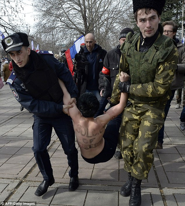 Crackdown: A Ukrainian police officer (left) and a pro-Russian volunteer (right) detain a Femen activist