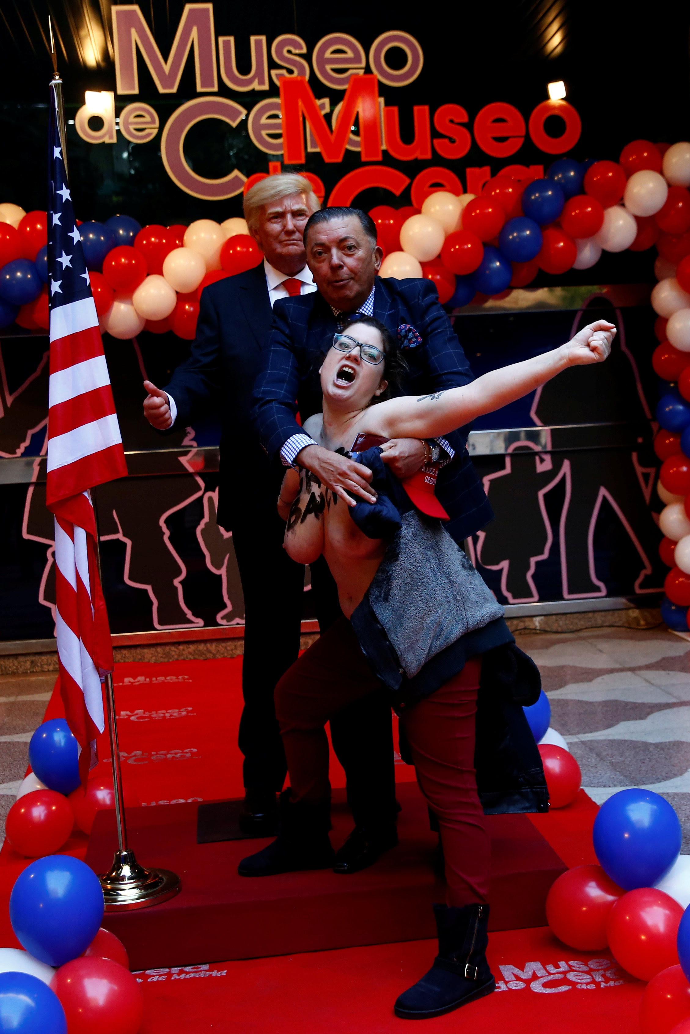 A museum worker tries to stop a topless activist from the feminist group FEMEN from grabbing the crotch of a life-sized wax statue of U.S. President-elect Donald Trump during an unveiling ceremony at Madrid's wax museum in Madrid, Spain, January 17, 2017. REUTERS/Susana Vera TEMPLATE OUT