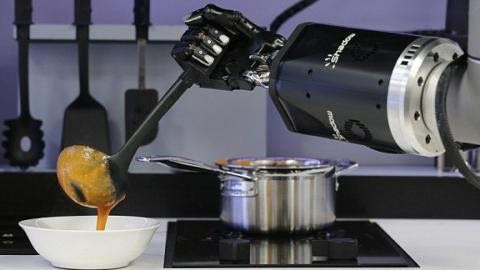 Robotic arms serve a soup prepared on stovetop.