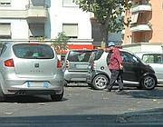Un abusivo fa segno a un automobilista di parcheggiare in doppia fila (foto Proto)