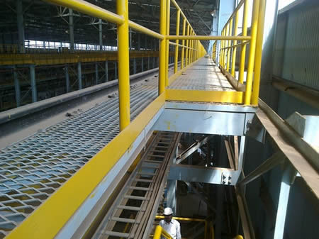 A man is steps on the expanded metal grating gantry platform.