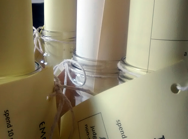 Handouts on pale yellow paper rolled and tucked into jars, with instructions tied on with string