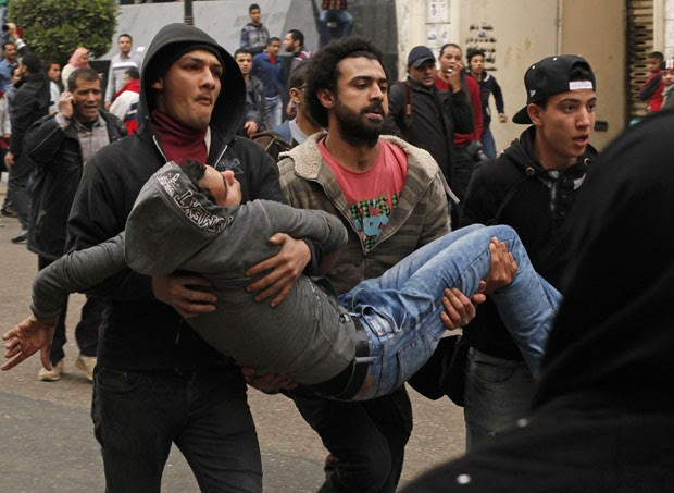 Manifestantes ajudam ferido após pessoas pró-governo jogarem pedra em opositores no Cairo (Foto: Asmaa Waguih/Reuters)