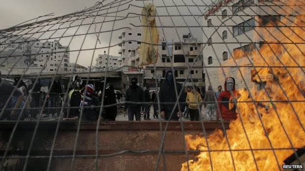 Palestinian stone-throwers stand behind garbage set ablaze during clashes with Israeli police on the streets of mainly Arab East Jerusalem (5 November 2014)