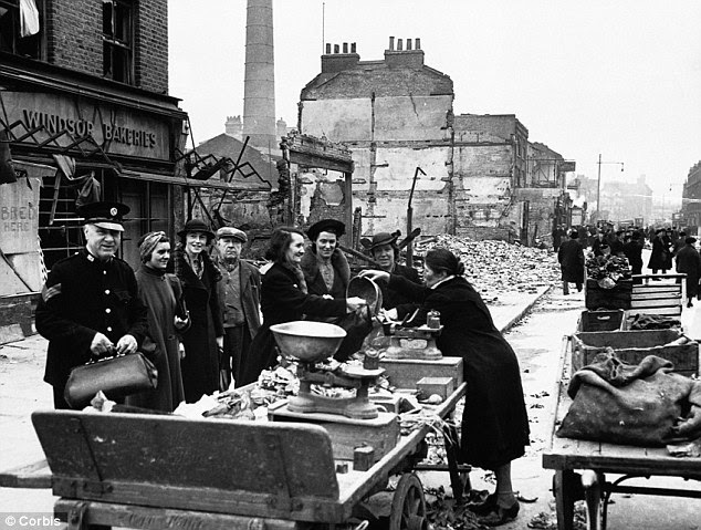 A greengrocer remains open for business at a market in Lambeth Way in London after a V-2 Bombing raid
