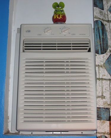 The bedroom A/C, abetted by vintage curtains and Rat Fink.