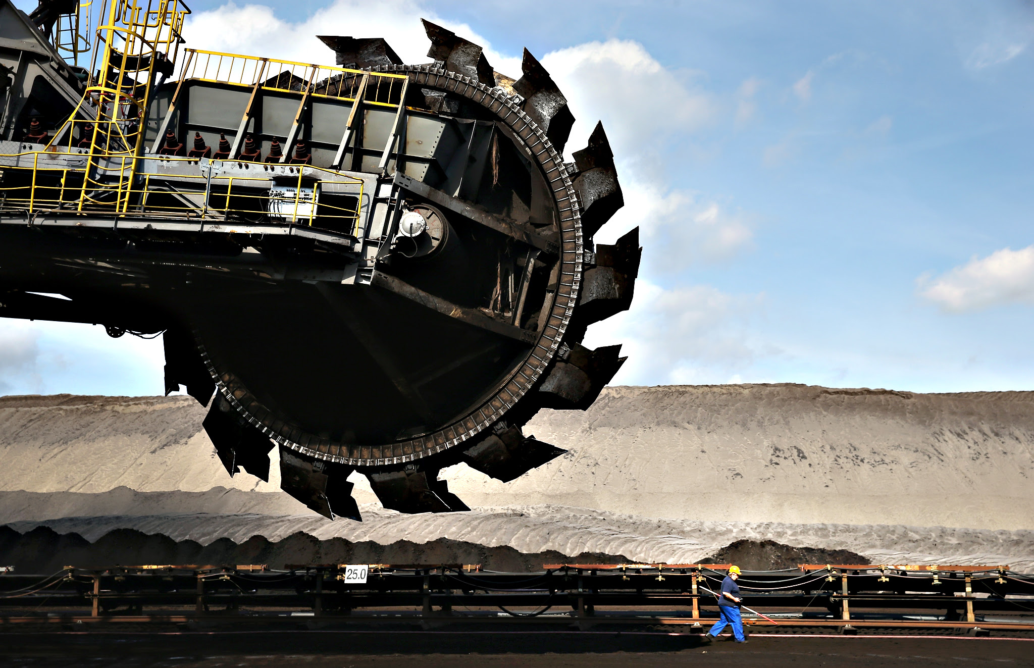 A worker walks past a bucket-wheel excavator in the Welzow Sued open-pit lignite coal mine on Friday near Welzow, Germany. The Welzow Sued mine feeds the Schwarze Pumpe and Jaenschwalde power stations and is owned by Vattenfall, the Swedish energy company that recently announced it will sell its eastern German coal mines and power plants. Before the communist government of East Germany collapsed in 1989 open-pit coal mines were a vital source of employment in the region and their decline has pulled the local economy down with them. 25 years since German reunification eastern Germany is struggling with a low birth rate, rural emigration and unemployment rates higher than in western Germany. The Welzow Sued mine is one of five left in the Lausatz region from 17 that existed in 1989. It is scheduled to remain in operation until 2042