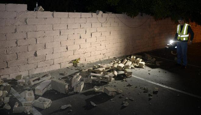 News cameraman Juan Guerra records a video of a fallen brick wall after a magnitude 5.1 earthquake in Fullerton, California March 29, 2014. REUTERS/Gene Blevins