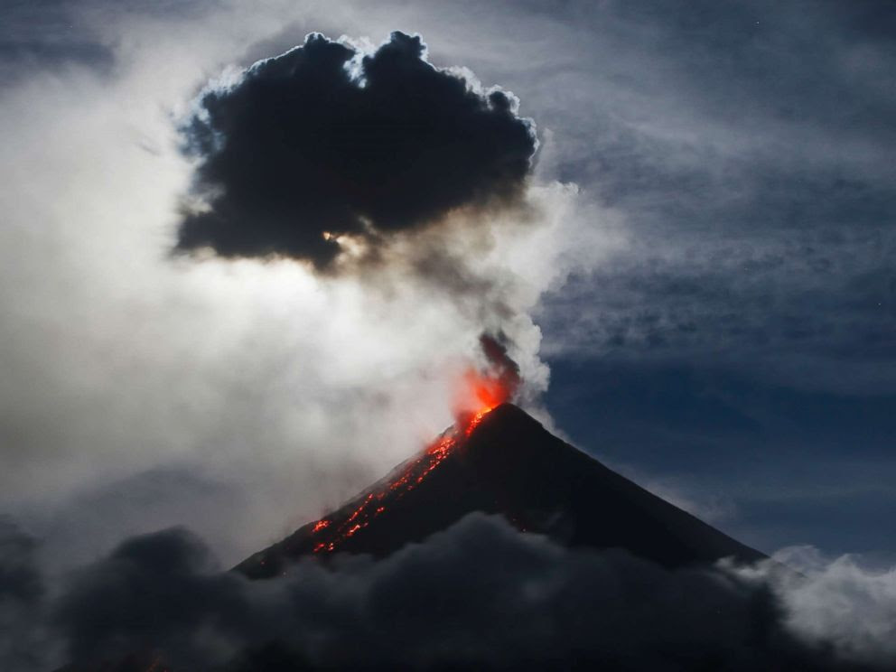 PHOTO: The super blue blood moon, behind volcanic ash cloud, sets before dawn as lava cascades down the slopes of Mayon volcano during a sporadic mild eruption around 200 miles southeast of Manila, Philippines, Feb. 1, 2018.