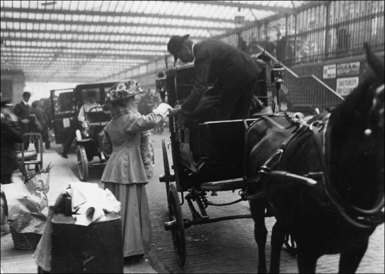 A woman pays a cab driver at Paddington Station