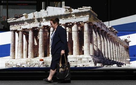 A woman walks past a bus featuring a picture of the temple of the Parthenon in central Athens May 22, 2012. REUTERS-John Kolesidis
