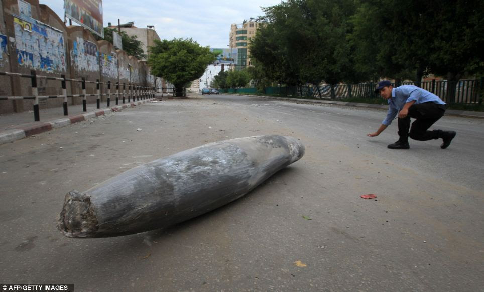 Unexploded bomb: A Palestinian Hamas policeman looks at an Israeli rocket in the street in Gaza City on Saturday