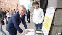 Pat Cox signing the petition in the street