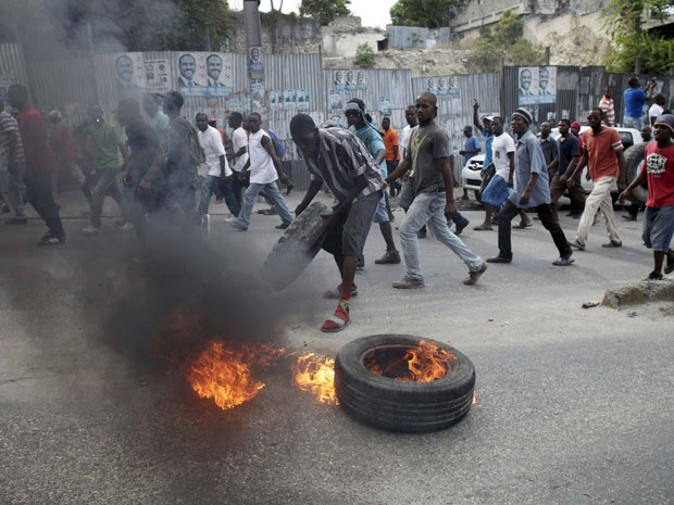 Manifestante coloca fogo em pneu durante protesto nesta sexta-feira (22) contra o processo eleitoral em Porto Príncipe, no Haiti (Foto: REUTERS/Andres Martinez Casares)