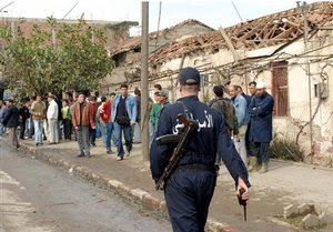 A police officer patrols near a damaged house in Si-Mustapha, near Boumerdes, 40 kilometers (25 miles) east of the capital, Algiers, Tuesday Feb.13, 2007 after a bomb exploded in the middle of the town, wounding five policemen.