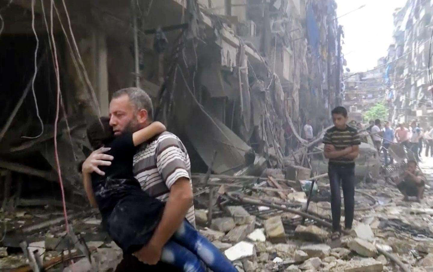 Un homme porte un enfant après des frappes aériennes sur Alep, Syrie, le 28 avril 2016. (Validated UGC via AP video)