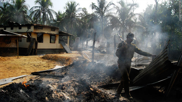 A security official inspects a house burned during an upsurge of violence between rival ethnic groups in northeast India.