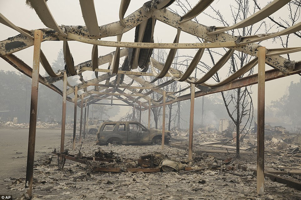 A carport frame and burned cars remain outside an apartment complex destroyed by fire Sunday in Middletown, California