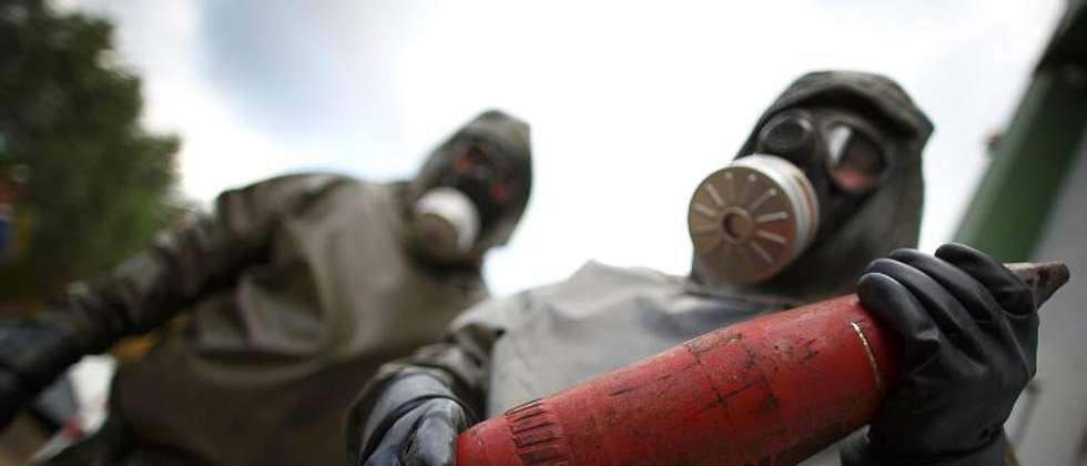 Employees in protective gear hold a dummy grenade during a demonstration in the chemical weapons disposal facility at GEKA, in Munster, northern Germany, on October 30, 2013 ( Philipp Guelland (AFP/File) )