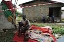 Suspected carrier of Ebola virus James Flomo sits in isolation with his children after his wife Lorpu Flomo died three days earlier in Monrovia