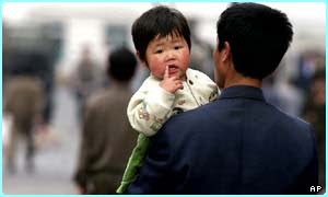 A father carries his young daughter along a street in Pyongyang, the capital of North Korea 