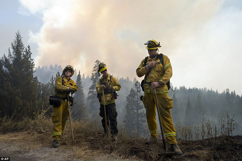 Waiting: Angel City fire fighters Cody Stephens, left, and Kevin Brown, center, wait as a helicopter dumps water on hot spots battling the Rim Fire in the Stanislaus National Forest