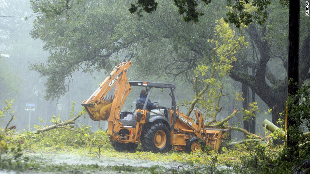 A worker in the driving rain tries to clear fallen limbs in the riverbound lanes of Espanade Avenue near McDonogh High School in New Orleans.