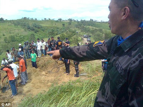 A member of the Philippine National Police points to the site where the bodies of 24 political supporters and journalists were found