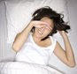 A young woman waking up in bed.