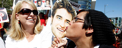Fan Yolanda Rodriguez (R) kisses a photograph of cast member Robert Pattinson. (REUTERS/Mario Anzuoni)