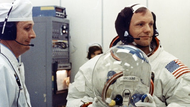 PHOTO: Apollo 11 Commander Neil Armstrong prepares to put on his helmet with the assistance of a spacesuit technician during suiting operations in the Manned Spacecraft Operations Building (MSOB) prior to the astronauts' departure to Launch Pad 39A.